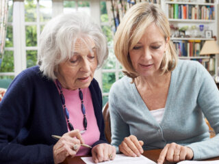 A daughter sits beside her mother, gently walking through senior living options together and turning a difficult topic into a calm, supportive discussion.