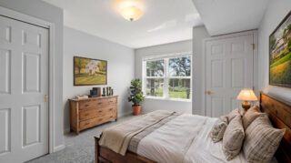 Apartment bedroom with natural light and comfortable furnishings in a senior living community in Newton, IA.
