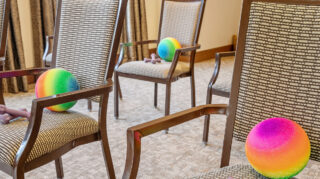 Chairs with exercise equipment for group movement activities in a senior living community in Newton, IA.