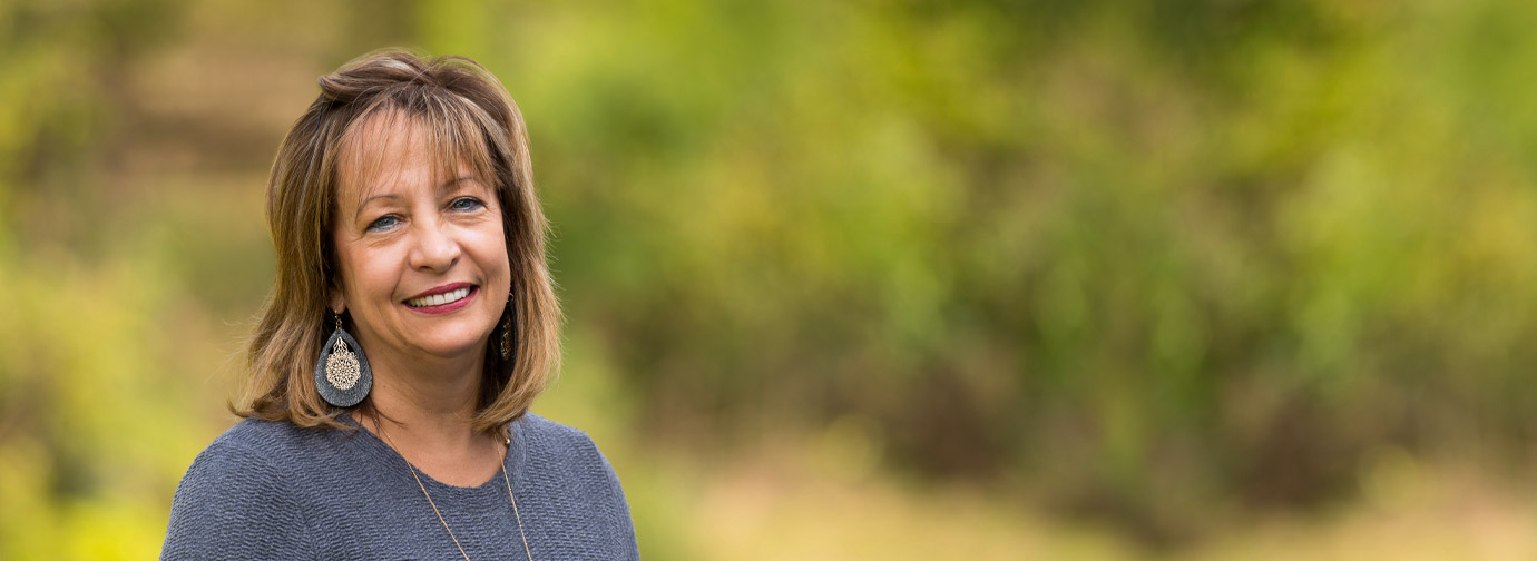 Employee portrait outdoors with a blurred natural background at Newton Village