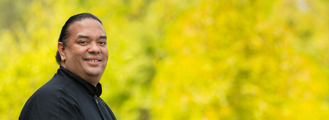 Employee portrait outdoors with a natural green background, representing staff like at Newton Village