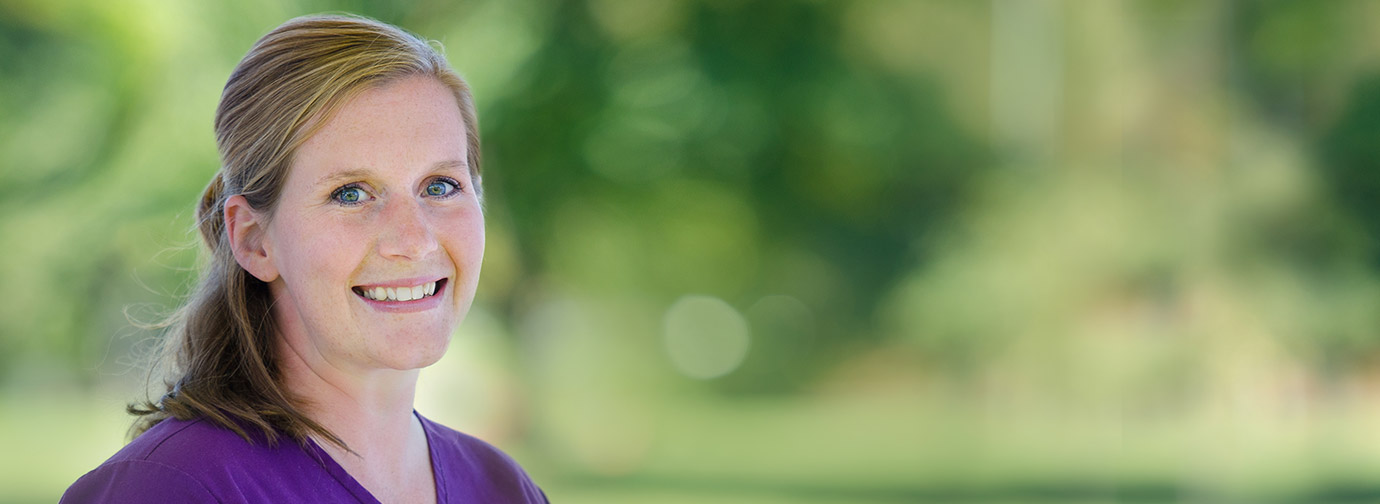 Employee portrait outdoors with a blurred green background, representing staff like at Newton Village