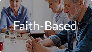 Group of adults seated at a table with heads bowed and hands together, with the text “Faith-Based” displayed, representing spiritual care and faith-based support like at Newton Village