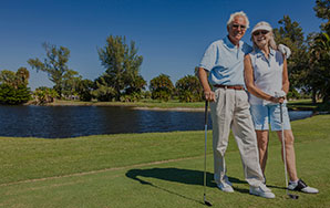 Two older adults standing on a golf course with clubs near a pond, representing an active outdoor lifestyle like at Newton Village