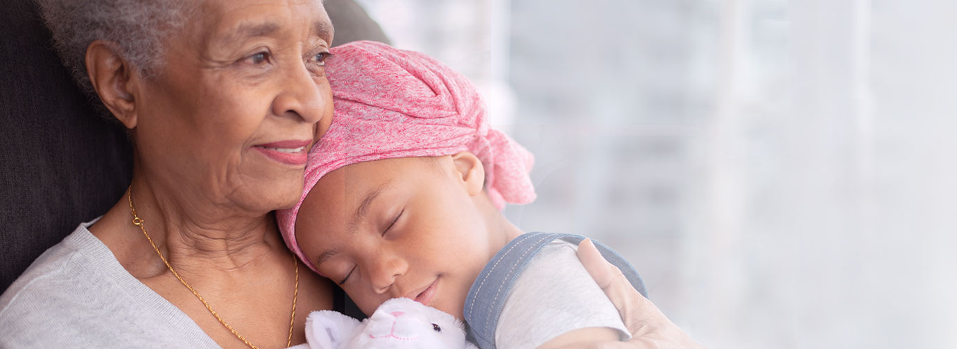Older adult holding a child resting against them with a small stuffed animal, representing compassionate hospice care and family support like at Newton Village