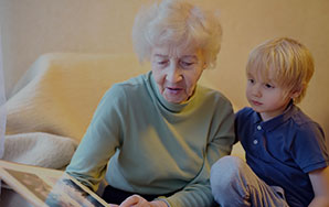 Older adult reading with a child seated nearby in a home setting, representing compassionate hospice care and family support like at Newton Village