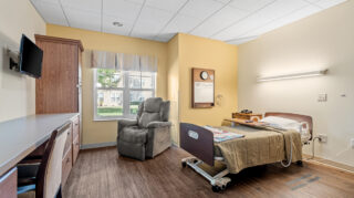 Private rehabilitation room with bed, seating, and window in a senior living community in Newton, IA.